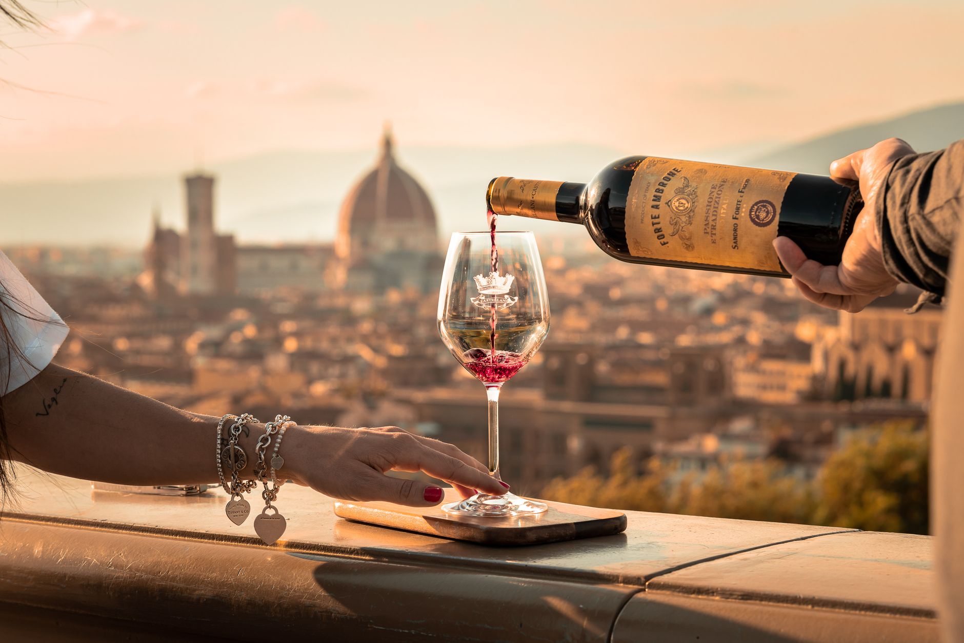 pouring wine to woman glass in sunlight and with town behind